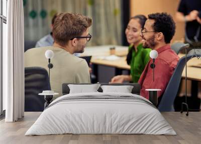 Group of young happy multi racial coworkers communicating and sharing ideas while working together in the modern office Wall mural