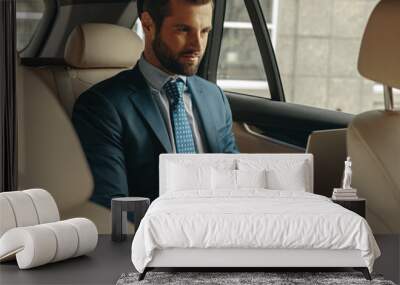 Handsome Caucasian businessman working online during the travel by car Wall mural