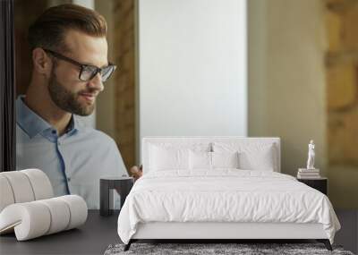 Handsome Caucasian man with his gadget at work Wall mural