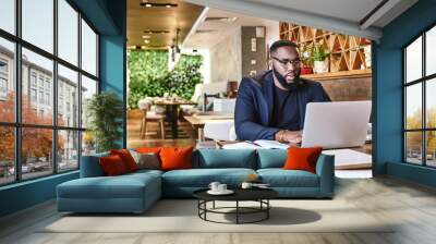 I learned the value of hard work by working hard. African american businessman is working, using his laptop while resting in the cafe Wall mural