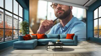 Lost in thougths. Portrait of young bearded man in eyeglasses and formal wear looking away and thinking while working in the modern office Wall mural