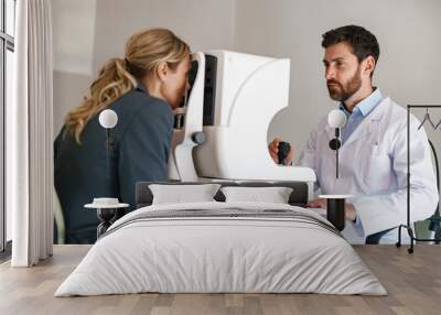 Male ophthalmologist checks a patient's vision at an opticians shop or ophthalmology clinic Wall mural