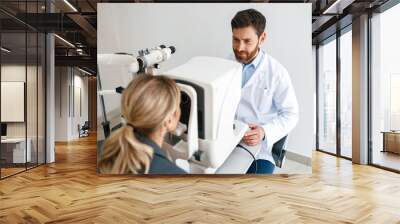 Male ophthalmologist checks a patient's vision at an opticians shop or ophthalmology clinic Wall mural