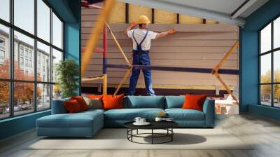 Male worker building cabin at construction site Wall mural