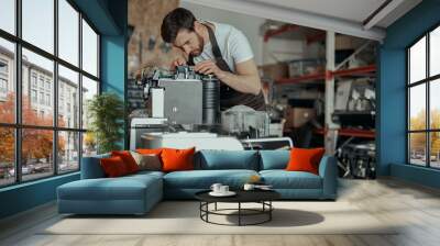 Man worker in uniform checking coffee machine in own workshop Wall mural