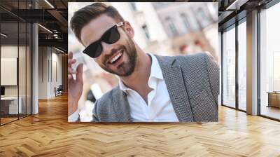 Portrait of a young handsome man, model of fashion, wearing tinted sunglasses in urban background Wall mural