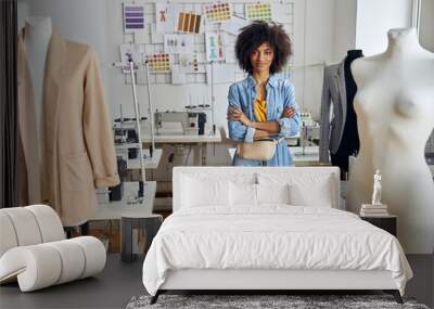 Positive African-American woman tailor stands at table with drawings in sewing workshop Wall mural