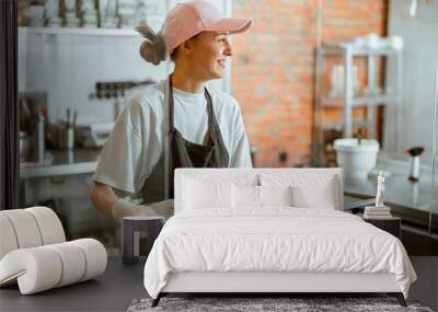 Pretty woman baker holds beautiful croissants with burnt albumenous cream in shop Wall mural