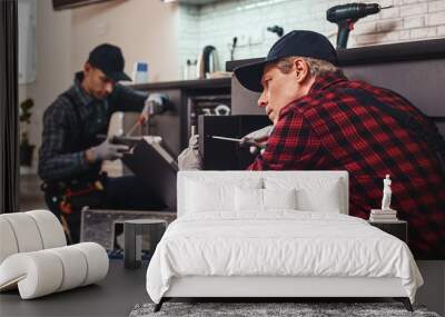 Quick and quality repairment. Two men technician sitting near dishwasher Wall mural