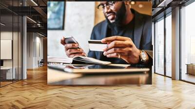 shot of african american businessman holding mobile and credit card, while resting in the cafe Wall mural