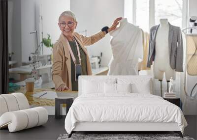 Smiling mature fashion designer stands between mannequin and cutting table in sewing workshop Wall mural