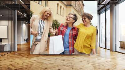 Smiling senior female friends is walking outdoors with shopping bags in the city center  Wall mural