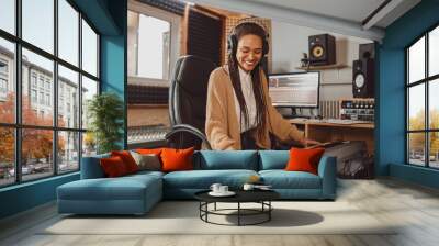 Stylish woman musician, sound composer playing synthesizer and rehearsing new song in the modern recording music studio Wall mural