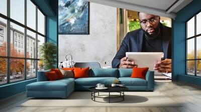 There are only two rules for being successful. One, figure out exactly what you want to do, and two, do it. Shot of a young afro american businessman using tablet while resting in the cafe Wall mural