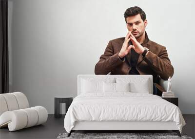 Waiting for interview. Stylish dark-haired man sitting on a chair, crossing his legs and looking at camera isolated over white background Wall mural