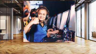 Winning. Two young happy professional cyber sport gamers giving fist bump and celebrating success while participating in eSports tournament Wall mural