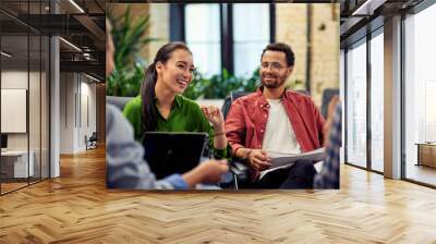 Young cheerful asian business woman discussing project results with colleagues while working together in the modern office Wall mural