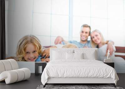 Young family lying on white bed Wall mural