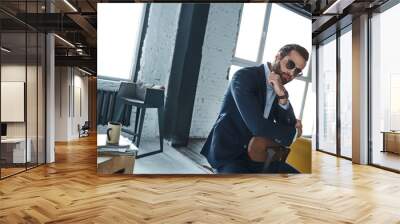 Young stylish businessman leader indoors at office wearing sunglasses looking aside thoughtful Wall mural