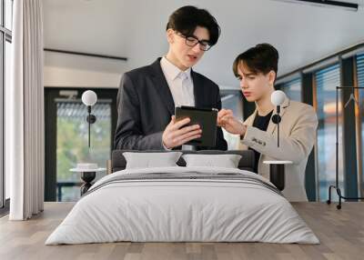 Two young workers discussing business affairs using a tablet in an office Wall mural