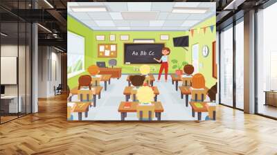 Cartoon kids and teacher in classroom, elementary school pupils studying. Young students listening to teacher at lesson vector illustration. Children sitting at desks and learning alphabet Wall mural