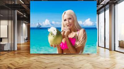 Beautiful blonde with long hair in bikini with coconut on a trop Wall mural