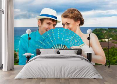 bride and groom with blue fan with a tropical beach in the backg Wall mural