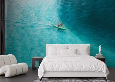 Surfing cruising in a nice blue water at sunrise. Beautiful top view of a surfer in the ocean Wall mural