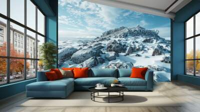 Snow-covered mountain hillside with rocks under clear blue sky Wall mural