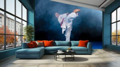 Pre-teen boy doing karate on a black background with smoke Wall mural