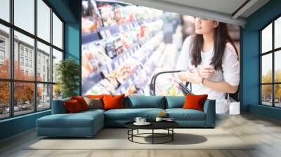 Asian beautiful woman shopping for dairy products at supermarket. healthy lifestyle concept Wall mural