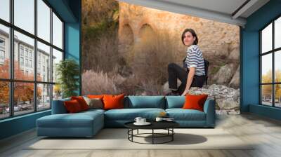 Young man posing in the field and with a bridge in the background. Enjoying the outdoors Wall mural