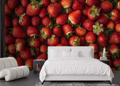 A close-up view of many fresh, ripe strawberries arranged in a pattern, with green leaves and a green background. Wall mural