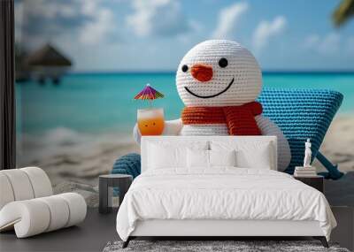 A smiling knitted snowman relaxes in a beach chair with a tropical drink on a white sandy beach with blue ocean water in the background. Wall mural