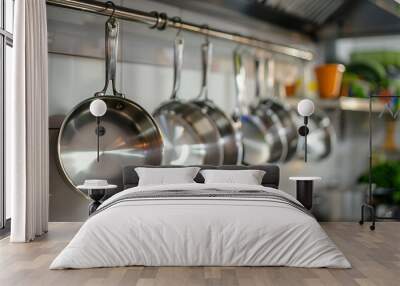 Closeup of a row of stainless steel pots hanging in a kitchen. Wall mural