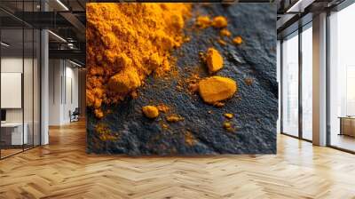 Closeup of yellow turmeric powder scattered on a black surface. Wall mural