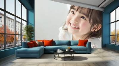 Portrait of a happy young girl smiling and looking up with a white background. Wall mural