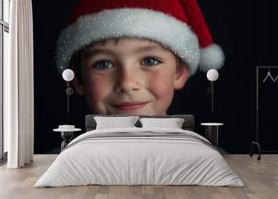 Portrait of a young boy wearing a Santa hat, smiling, looking at the camera. Wall mural