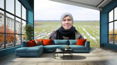 face portrait of a young guy 21-22 years old against a background of green snowy spring grass Wall mural