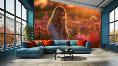 A young woman in a blooming garden, praying amidst flowers as the sun sets, symbolizing growth and renewal. Wall mural