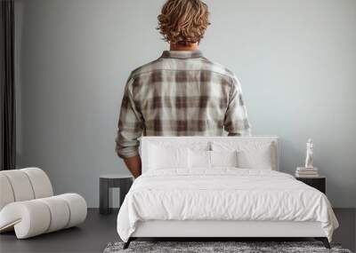 back view of young man in casual attire walking confidently against pure white background posture and stride conveying purpose and determination Wall mural