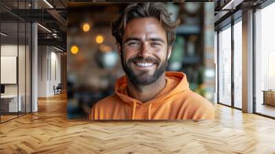 charismatic bearded man in tangerine hoodie genuine smile twinkling eyes urban loft backdrop warm ambient lighting Wall mural