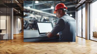 Male car factory engineer in work uniform using laptop with blank white screen at automotive industrial manufacture vehicle production. Wall mural