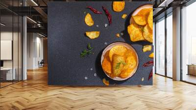 Bowls of homemade potato chips served with chili, parsley, seal salt on black stone background Wall mural