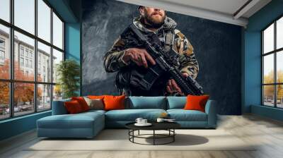 Bearded special forces soldier in the military camouflaged uniform holding an assault rifle. Studio photo against a dark textured wall Wall mural