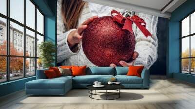 Big red Christmas ball in girl's arms. Wall mural