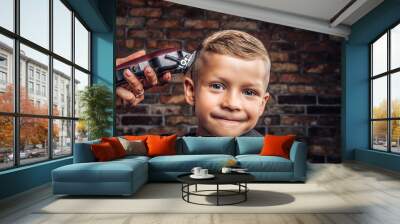 Close-up portrait of a cute smiling boy getting haircut against a brick wall. Wall mural