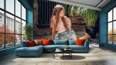 Cute girl sits on a floor in a living room. Wall mural