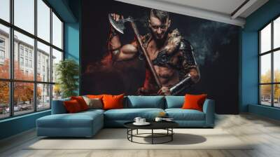 Dressed in light armour with fur scandinavian seafarer armed with two handed axe poses in dark background. Wall mural