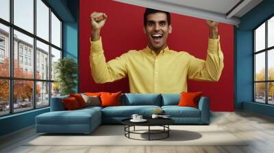 Enthusiastic man celebrates with fists in the air. Wall mural